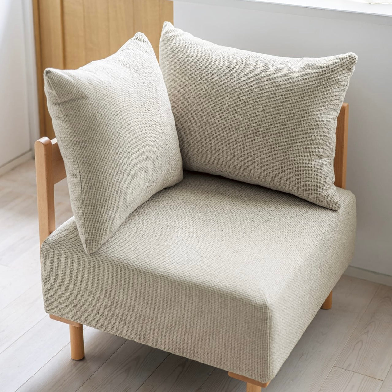 木製フレームのベージュのソファに人が座っている様子