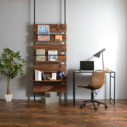 ブラウンの突っ張りディスプレイラックをデスク横に設置している様子