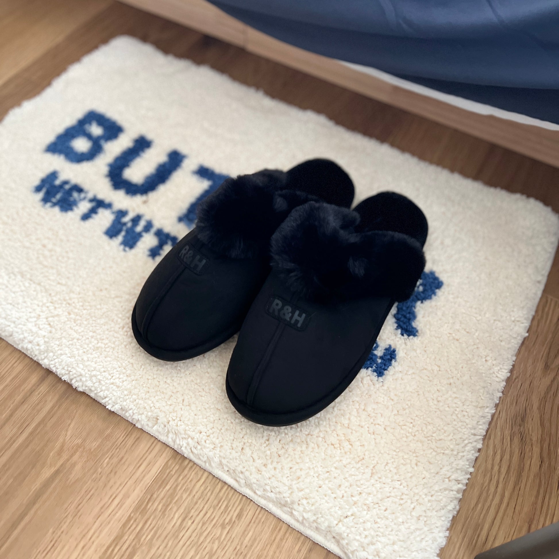 ブラックのムートン調のファースリッパをミニラグの上に置いている様子