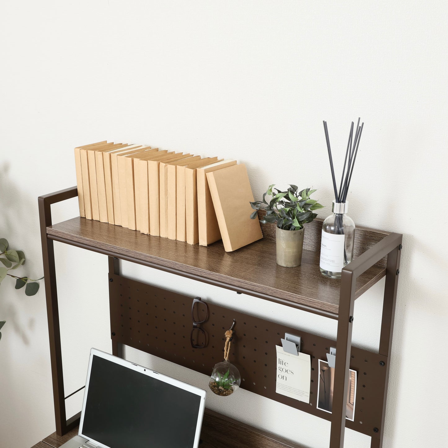 天板が折りたためる収納棚が付いたデスクにパソコンや本が置かれている様子