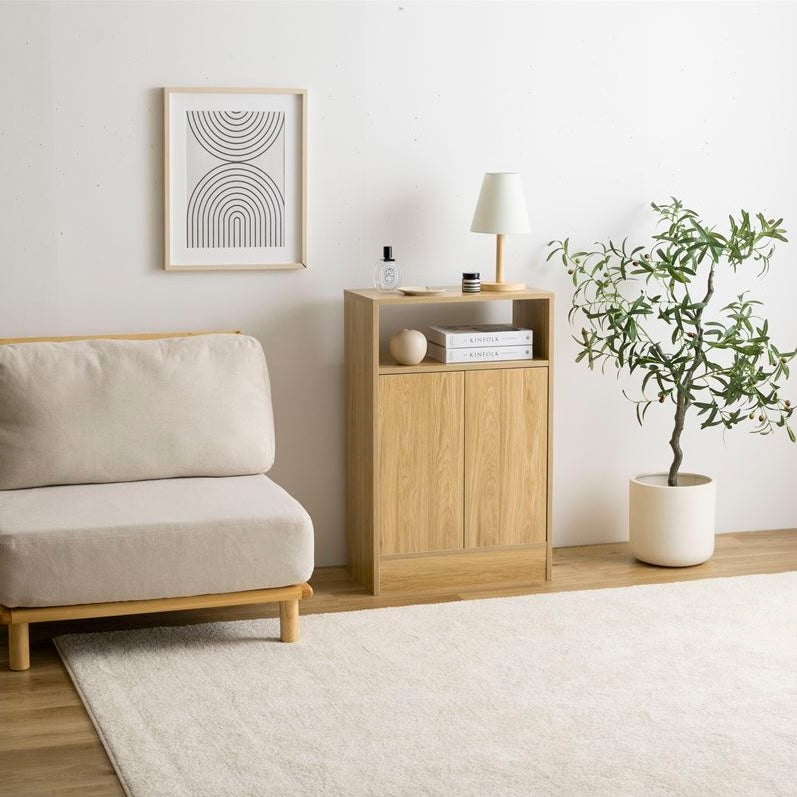 ナチュラルウッドの扉付きの収納とオープン棚が組み合わさったキャビネットを部屋の中でソファの横に置いている
