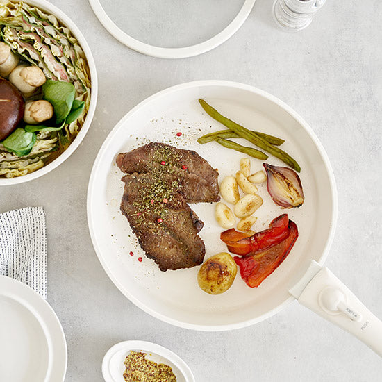 取手も本体も真っ白でお洒落な鍋で作った料理が食卓に並んでいる様子