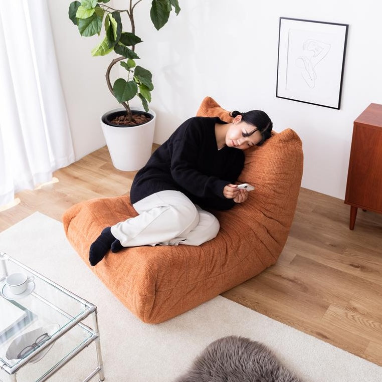 曲線フォルムと低重心デザインがお洒落なオレンジ色の1人掛けソファが部屋に置いてあるインテリア