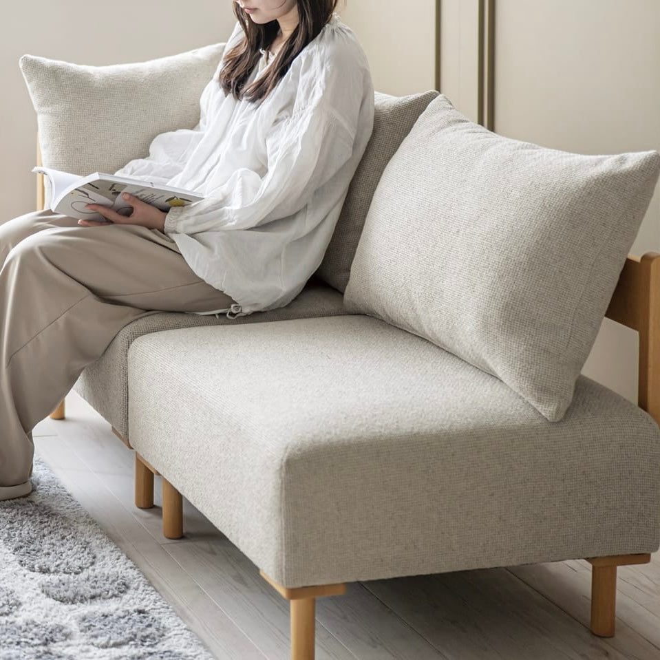 木製フレームのベージュのソファに人が座っている様子