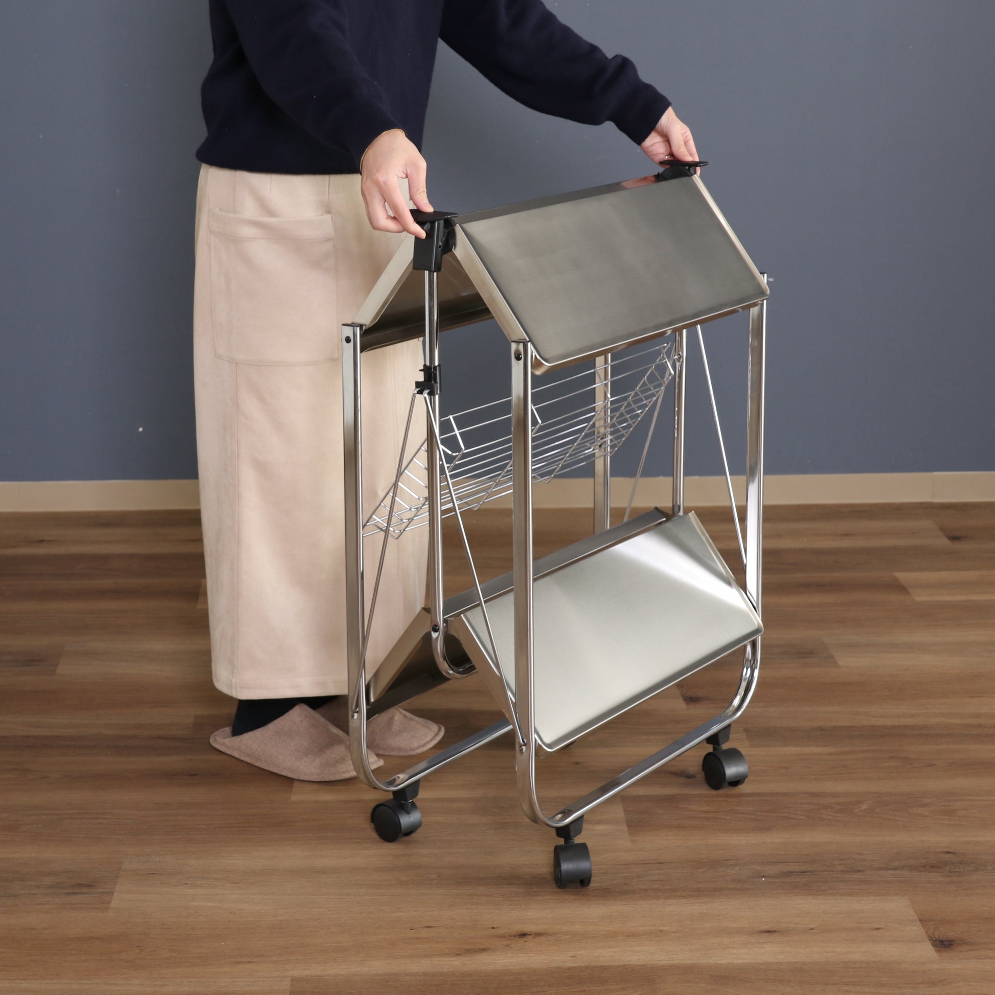 シルバーのフォールディングワゴンを折りたたんでいる様子