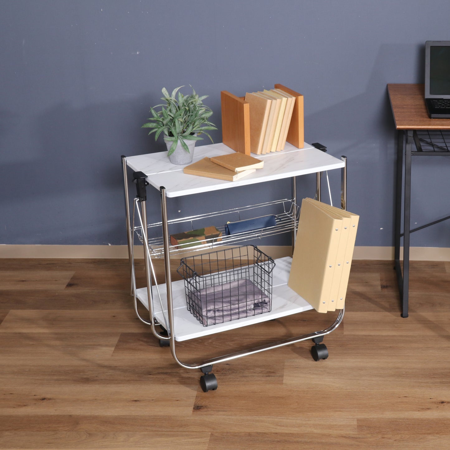 ホワイトのフォールディングワゴンに植物や本、書類などが置かれてある様子