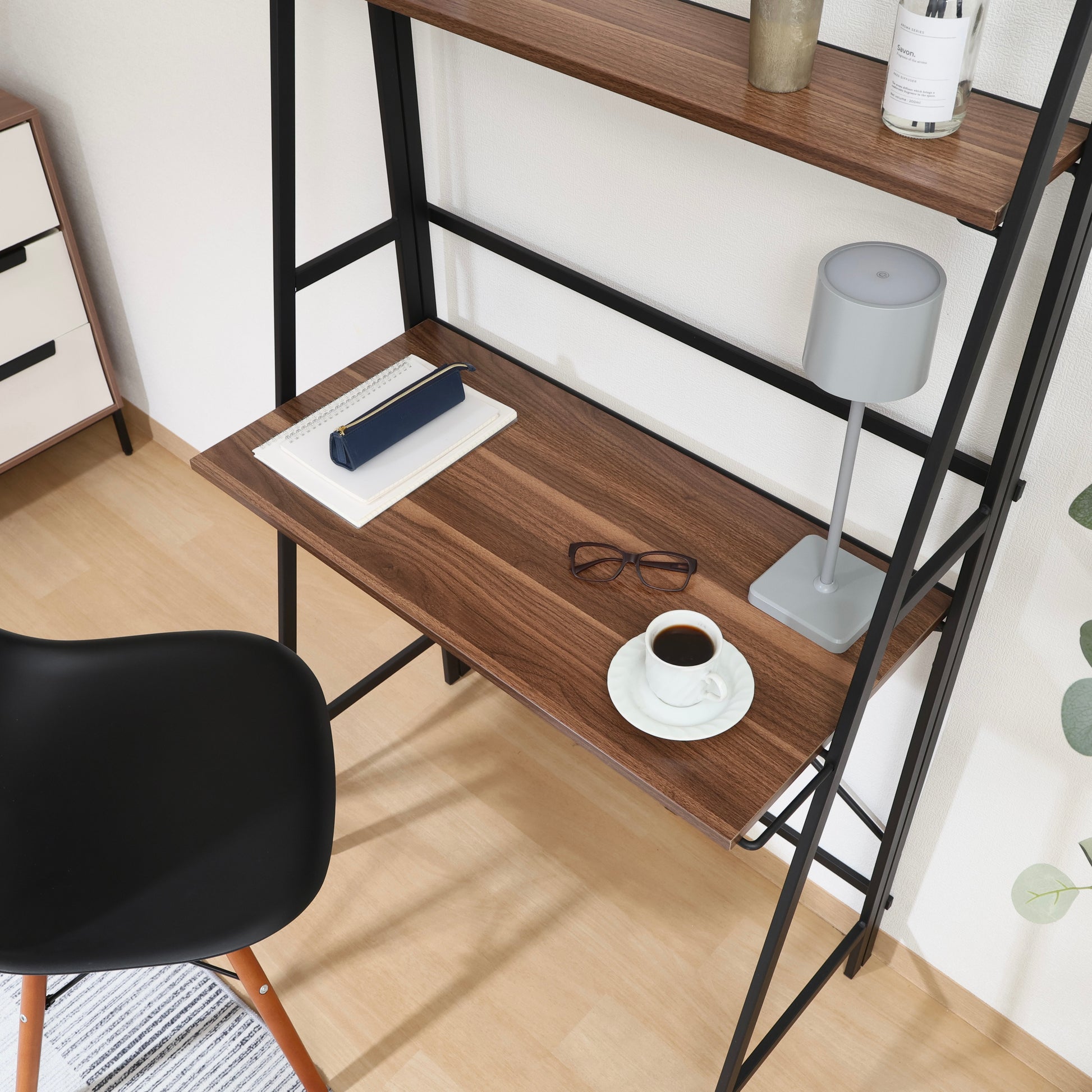 収納棚が付いた折りたたみ式のデスクにライトやコーヒーが置かれている様子