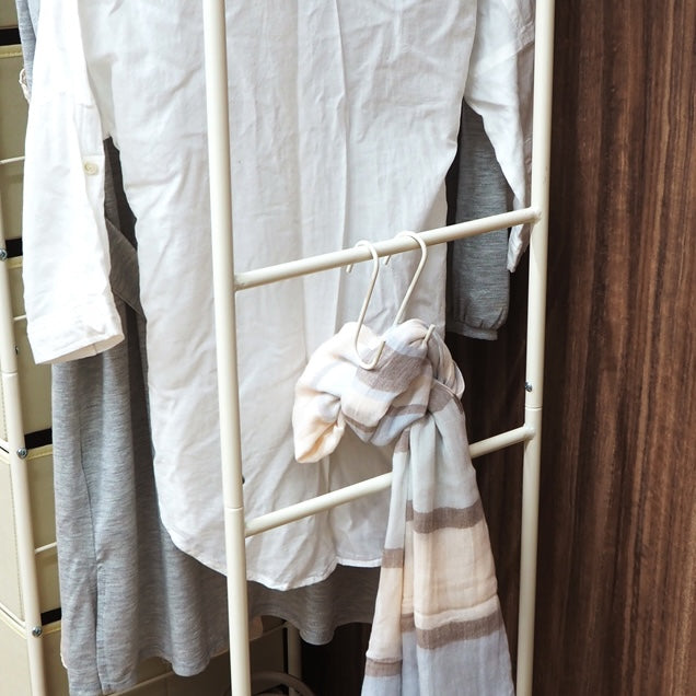 アイボリーの衣類を掛けるハンガーポールと7杯の引き出しを組み合わせた多機能なハンガーラックのサイドのポールにS字フックをかけている様子