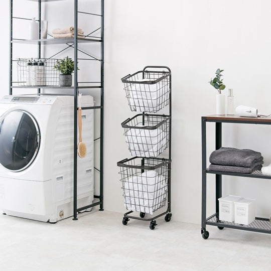 ダークブラウンのキャスター付き3段角型バスケットランドリーラックを洗濯機の横に置いている様子