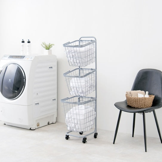 ブルーのキャスター付き3段角型バスケットランドリーラックを洗濯機の横に置いている様子