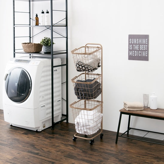 キャメルのキャスター付き3段角型バスケットランドリーラックを洗濯機の横に置いている様子