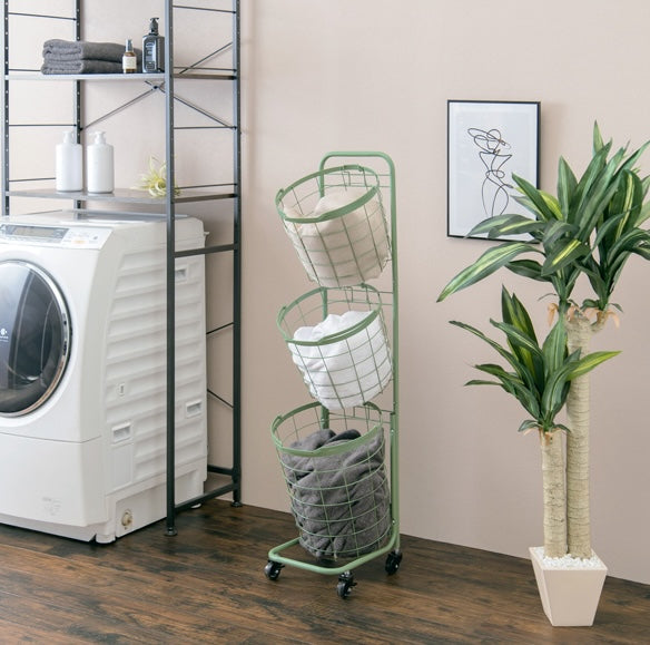 グリーンのキャスター付き3段丸型バスケットランドリーラックを洗面所に置いている様子