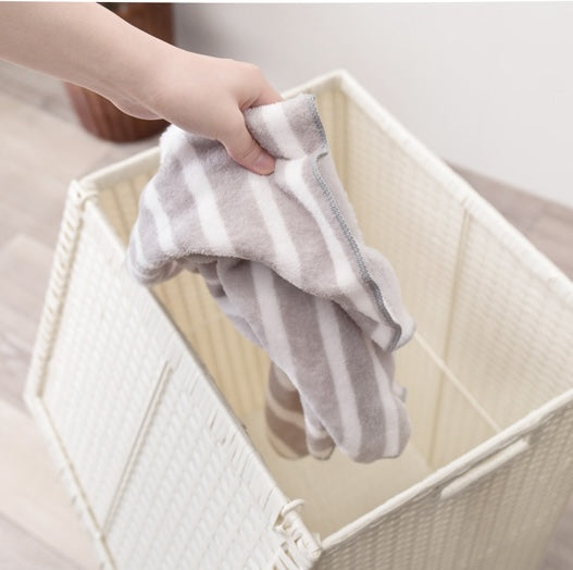ホワイトのキャスター付ラタン調収納ボックスにタオルを入れようとしている様子