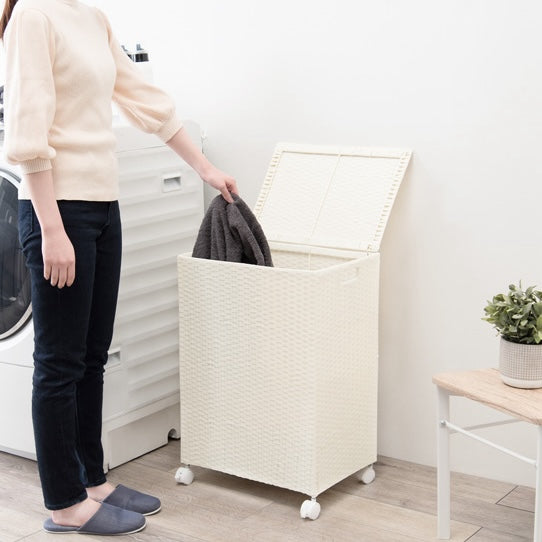 ホワイトのキャスター付ラタン調収納ボックスにタオルを入れようとしている様子
