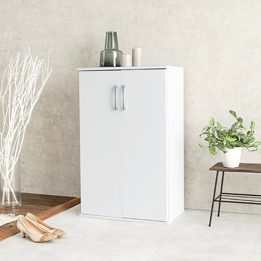 ホワイトのシューズラックの上に花瓶やキャンドルが飾られている