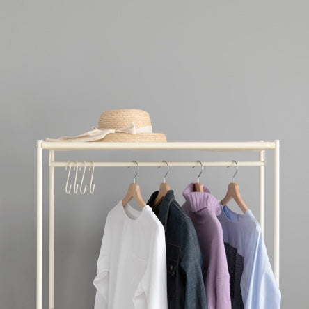 ファブリック素材の収納付きハンガーラックの上に帽子が置かれている