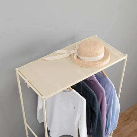 ファブリック素材の収納付きハンガーラックの上に帽子が置かれている