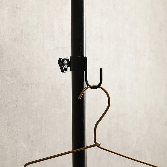 トレイ部分が丸型の突っ張りポールラックに洋服がかけられている