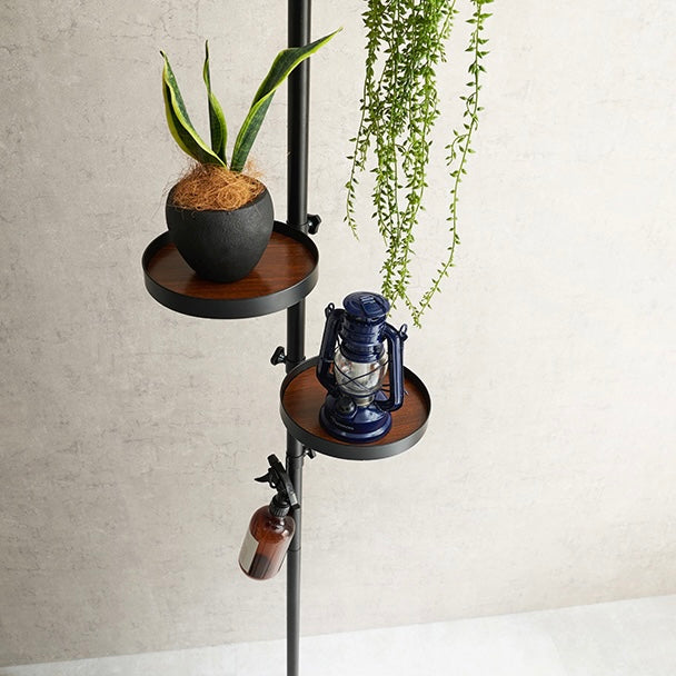 トレイ部分が丸型の突っ張りポールラックに植物か照明が置かれている