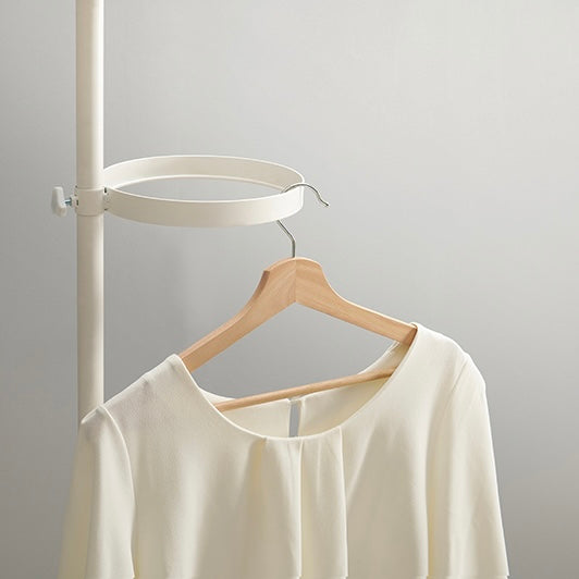 トレイ部分が丸型の突っ張りポールラックに洋服がかけられている
