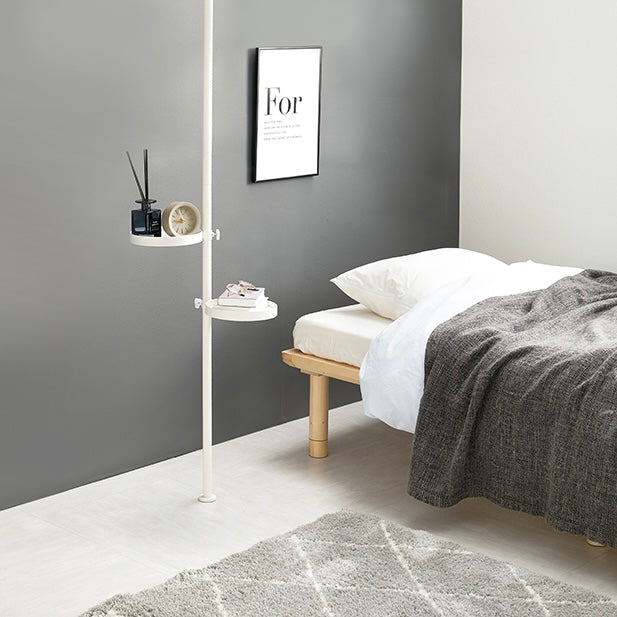 寝室に設置されているトレイ部分が丸型の突っ張りポールラックの本や時計が置かれている