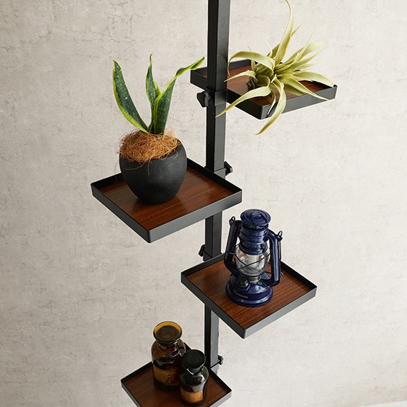 四角いトレイの突っ張りポールラックに植物や照明が置かれている