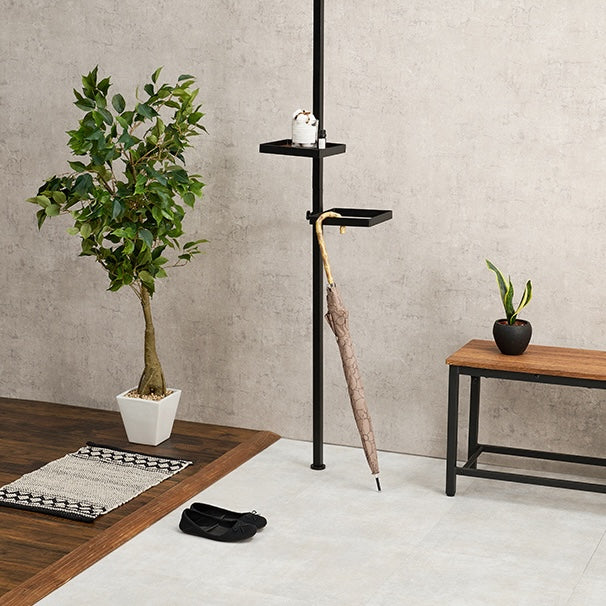 玄関に設置された四角いトレイの突っ張りポールラックに傘が置かれている