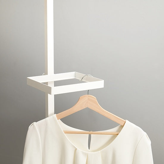 四角いトレイの突っ張りポールラックに洋服がかけられている