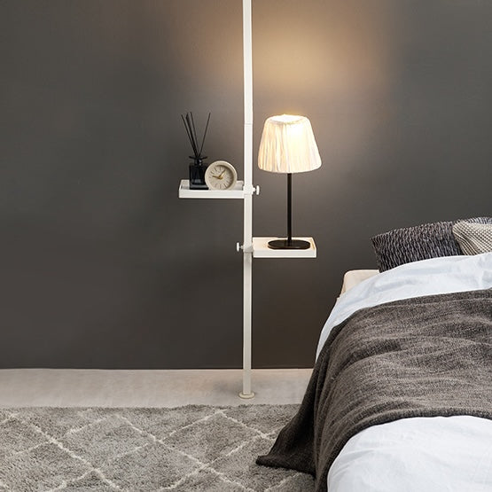 四角いトレイの突っ張りポールラックがベッド横に設置されている