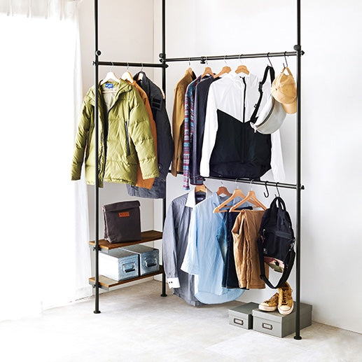 ブラウンの突っ張り伸縮ハンガーラックを部屋の角に設置している様子