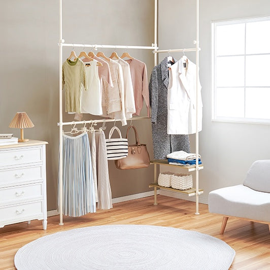 ホワイトの突っ張り伸縮ハンガーラックを部屋の角に設置している様子