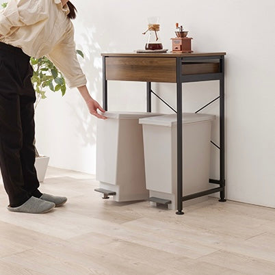 ブラウンのゴミ箱上収納の下に置かれたゴミ箱に手を掛けている