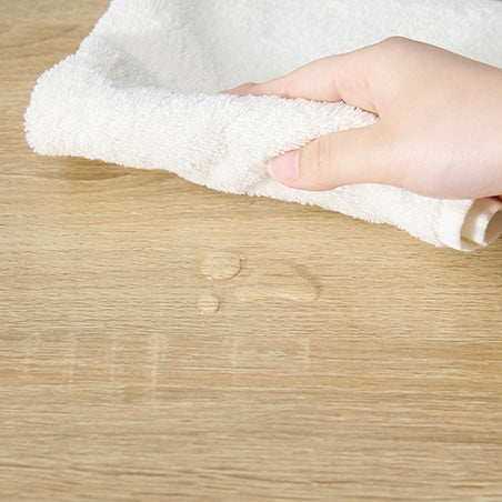 ナチュラルカラーのゴミ箱上収納が濡れていてタオルで拭こうとしている人の手