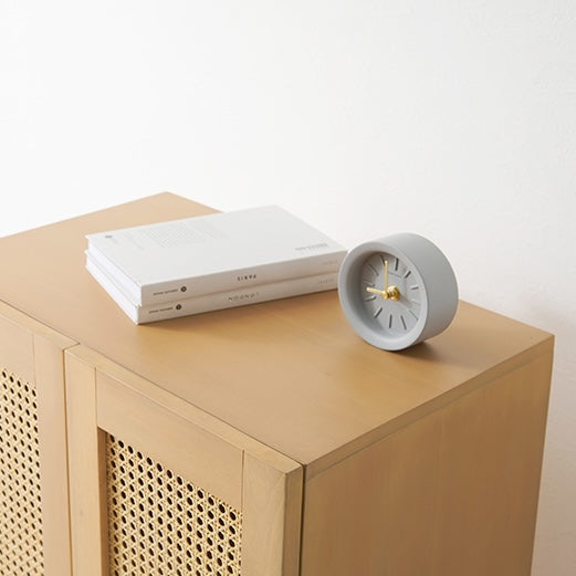 ラタン収納キャビネットの棚上に時計を置いている様子