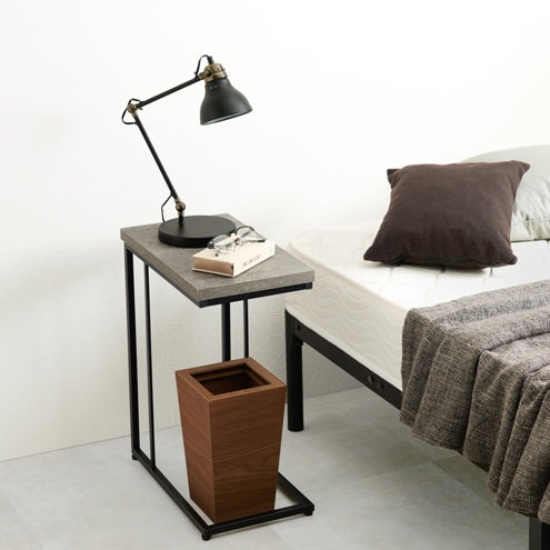 コンクリ風デザインのサイドテーブルがベッドサイドに置かれている部屋の様子