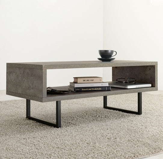 コンクリート風のスタイリッシュなローテーブルの収納部分に本やパソコンをしまっている様子