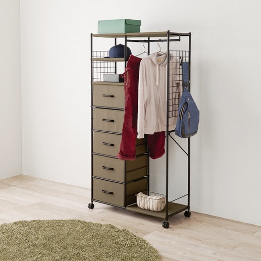 ブラウンのファブリック収納付きハンガーラックを部屋に置いている様子
