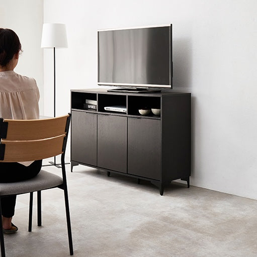 ブラックの木目調のキャビネットをテレビ台として置いている様子