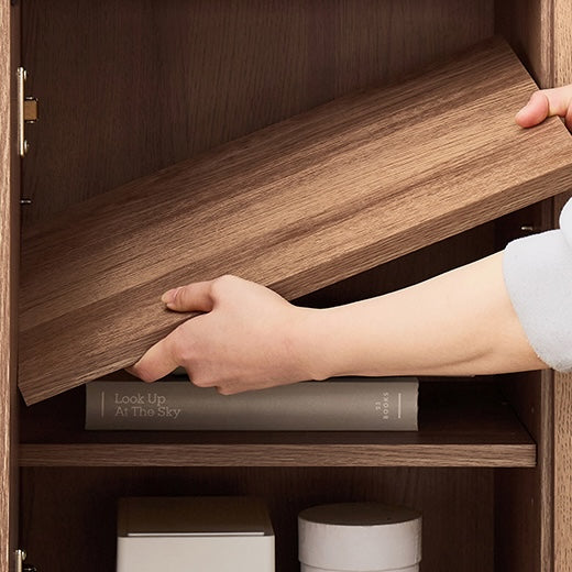 ブラウンの木目調のキャビネットの棚板を取り外している様子