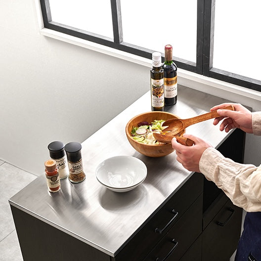 ダークブラウンのステンレス天板コンセント付きキッチンカウンターで調理をしている様子