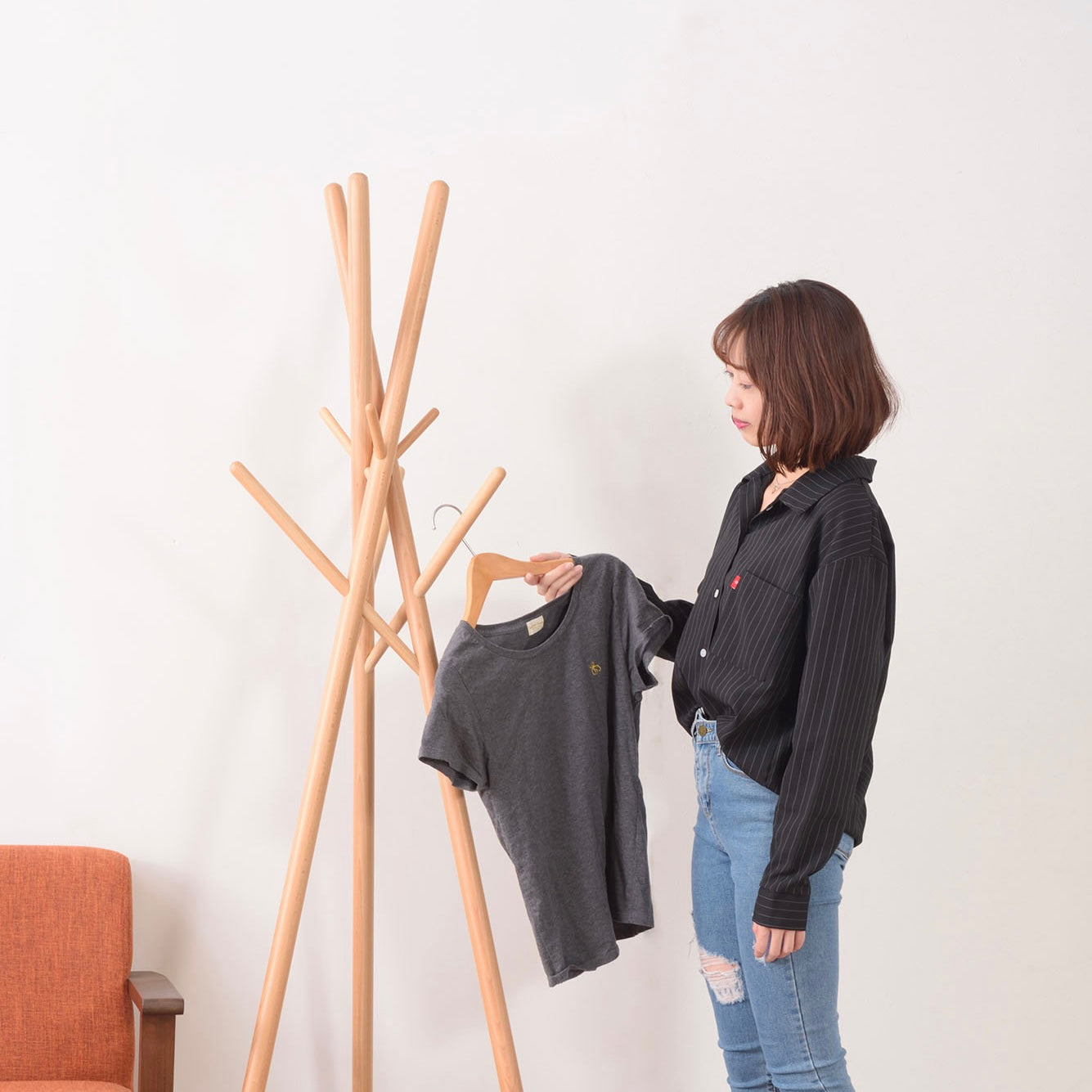 木の枝が交差したようなデザインのハンガーラックに服をかけている様子