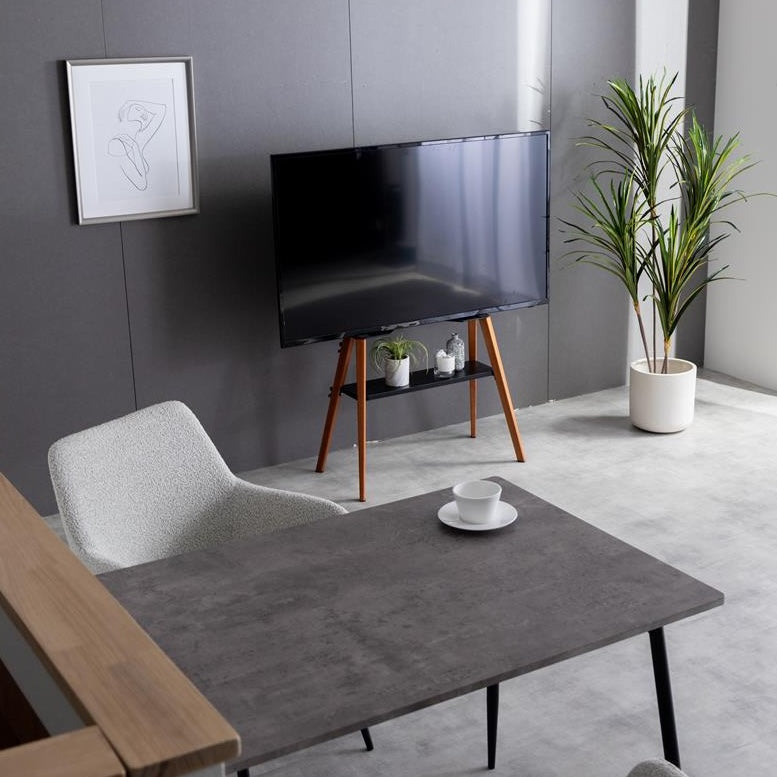 ブラックのラックが付いたウッド脚のテレビスタンドがリビングに置かれている様子