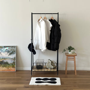 ブラックのスチール製のハンガーラックに洋服や帽子が掛けられている様子