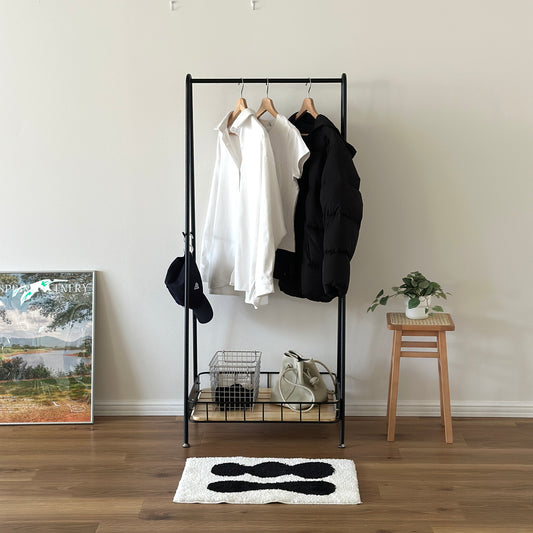 ブラックのスチール製のハンガーラックに洋服や帽子が掛けられている様子