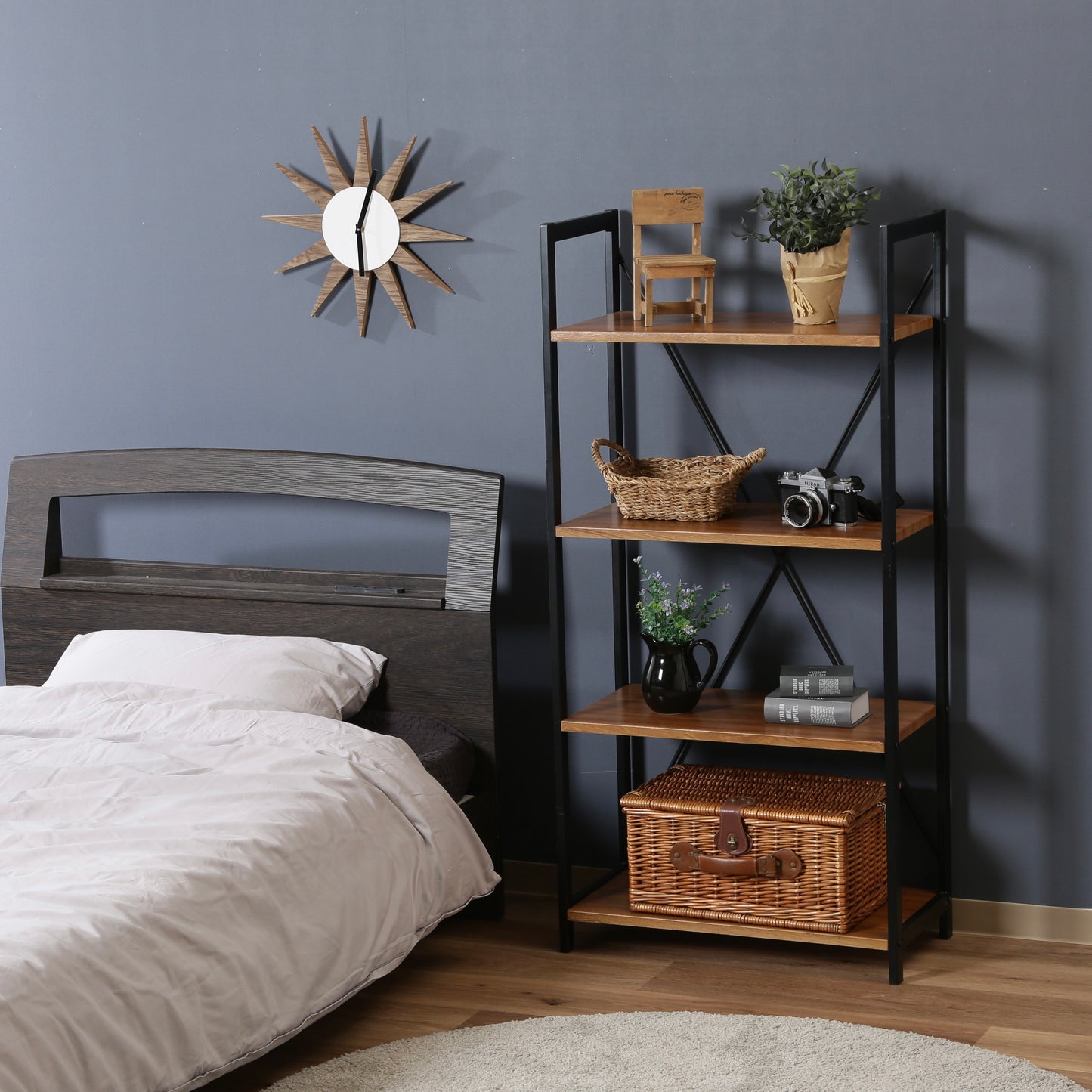 ウッド素材の天板と黒スチールのフレームの4段シェルフがベッド横に置かれている様子