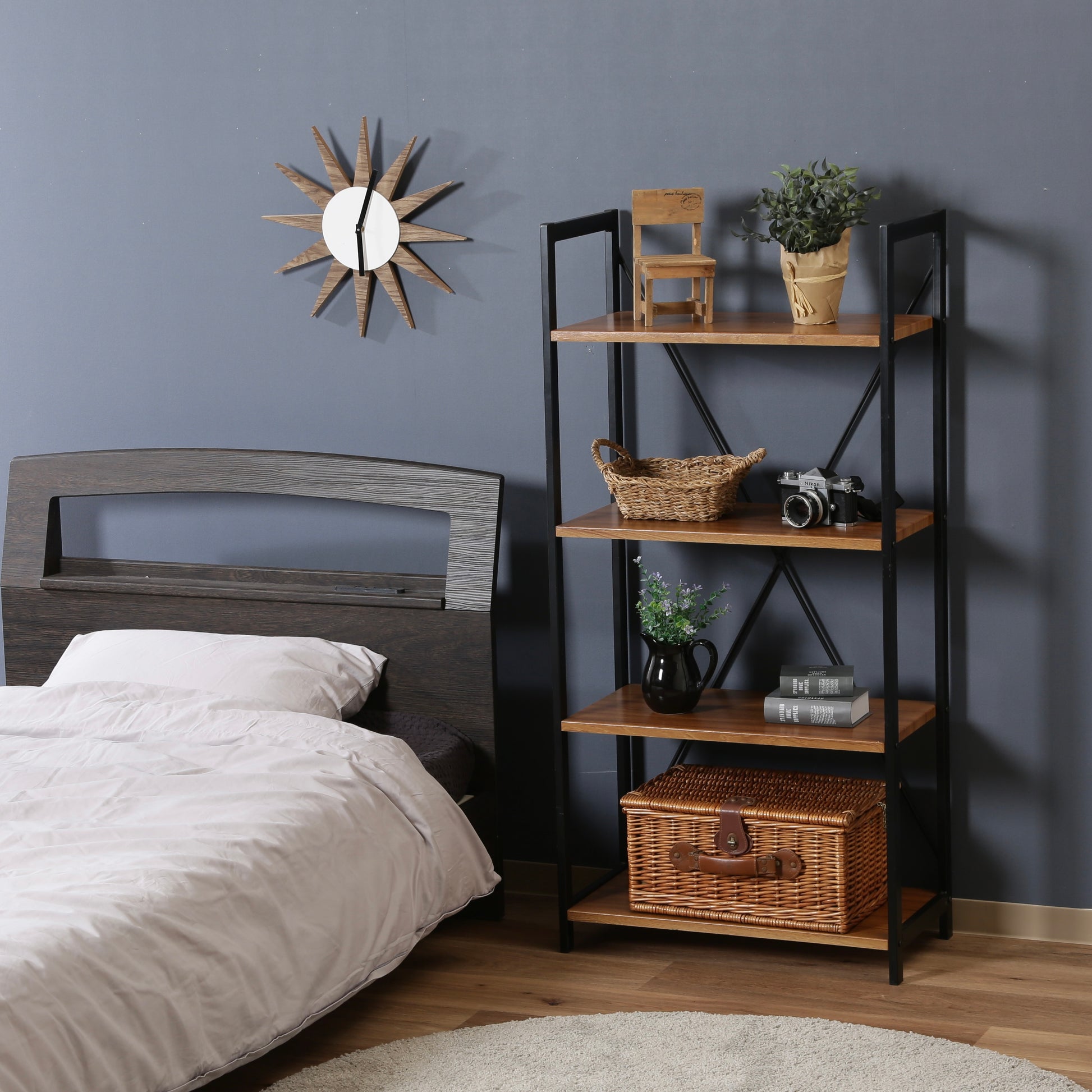 ウッド素材の天板と黒スチールのフレームの4段シェルフがベッド横に置かれている様子