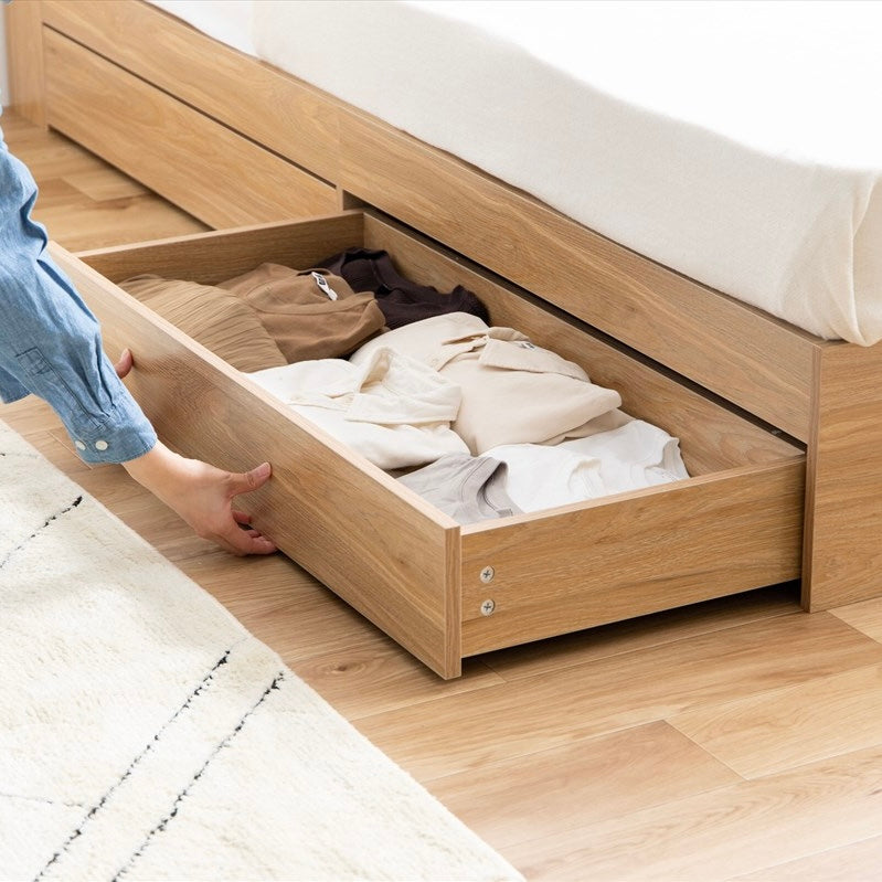 ナチュラルカラーの収納付きベッドフレームに収納されている衣類