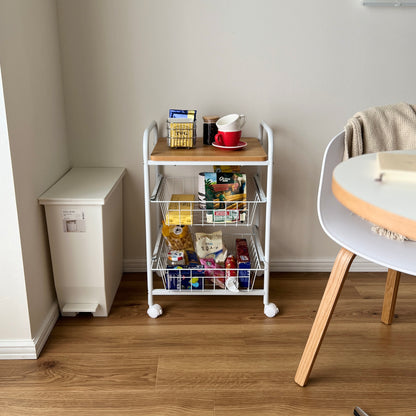 木目の天板とスチールフレームのキッチンワゴンに食料品を収納している様子