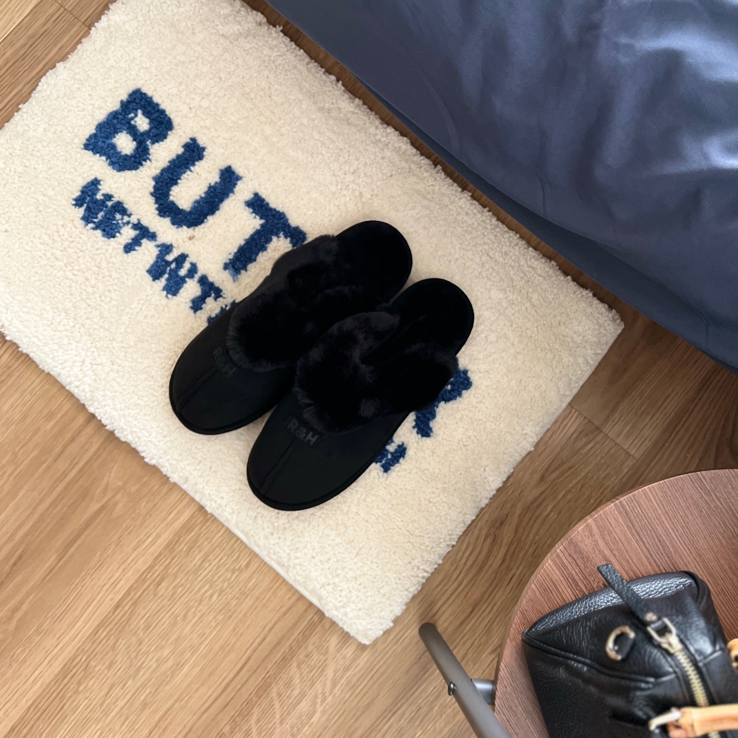 ブラックのムートン調のファースリッパをミニラグの上に置いている様子