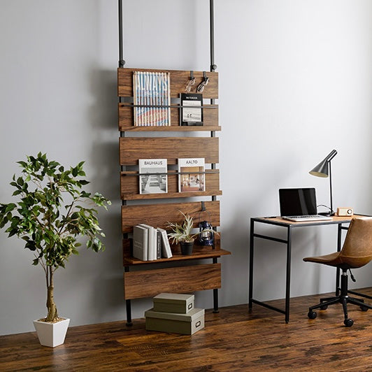 ブラウンの突っ張りディスプレイラックをデスク横に設置している様子